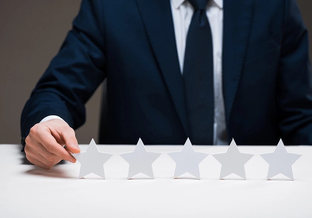 A businessman in a suit showcasing social proof with five stars on a table.