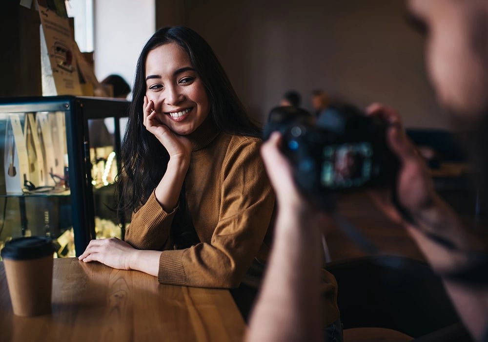 A Social Media Influencer is taking a picture with a camera in a coffee shop.