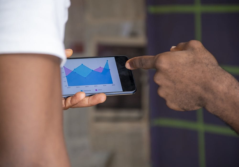 A person pointing at a graph on a mobile phone.