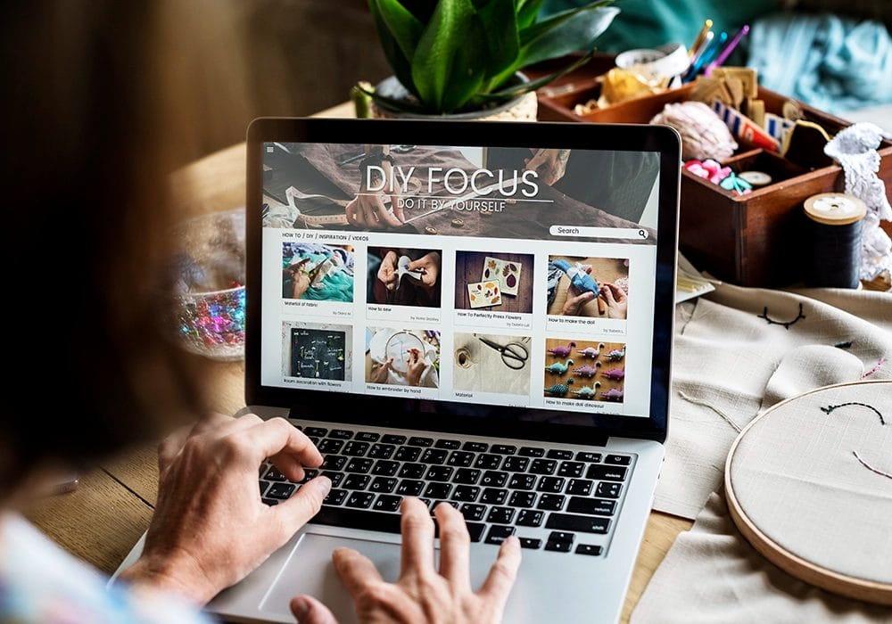 A person browsing a diy project website with a typical conversion rate on a laptop in a creative workspace.