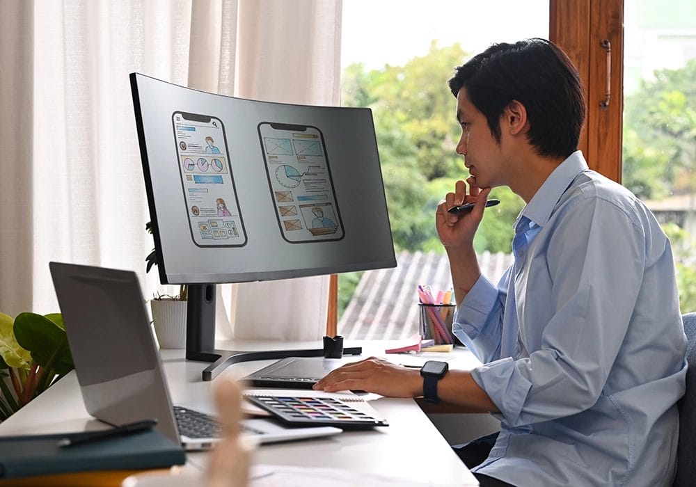 A man sitting at a desk looking at a computer screen, reviewing the UGC.