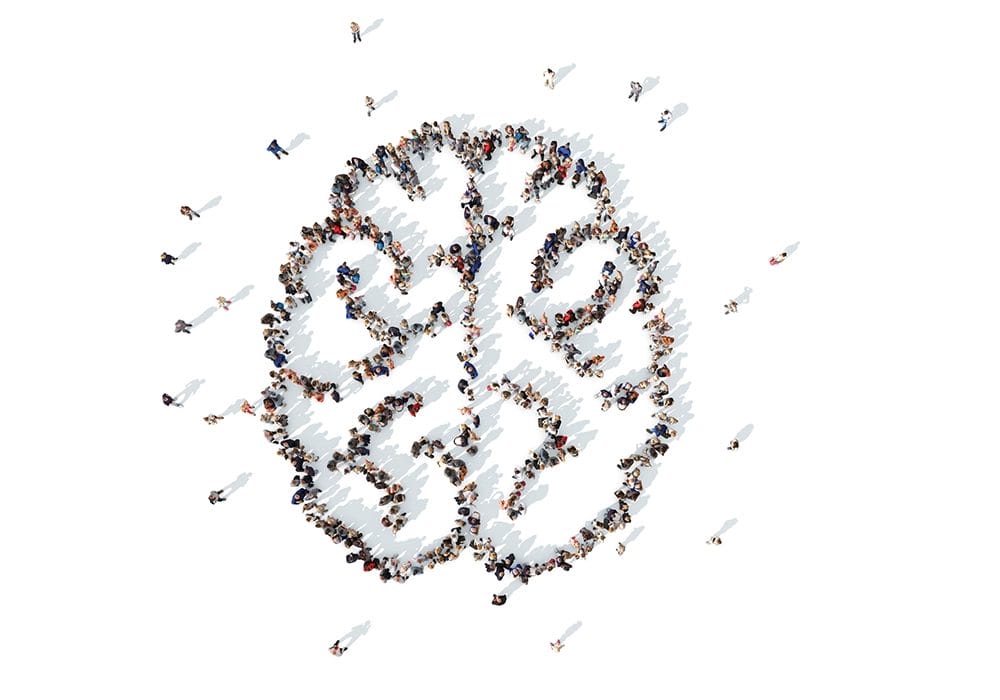 A large group of people forms the shape of a human brain when viewed from above, standing against a white background, illustrating the concept of social proof.