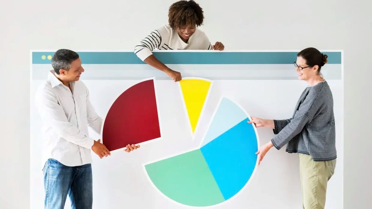 Three people stand behind a large pie chart graphic, each holding a different colored segment representing marketing performance indicators, and appear to be discussing or assembling the chart.
