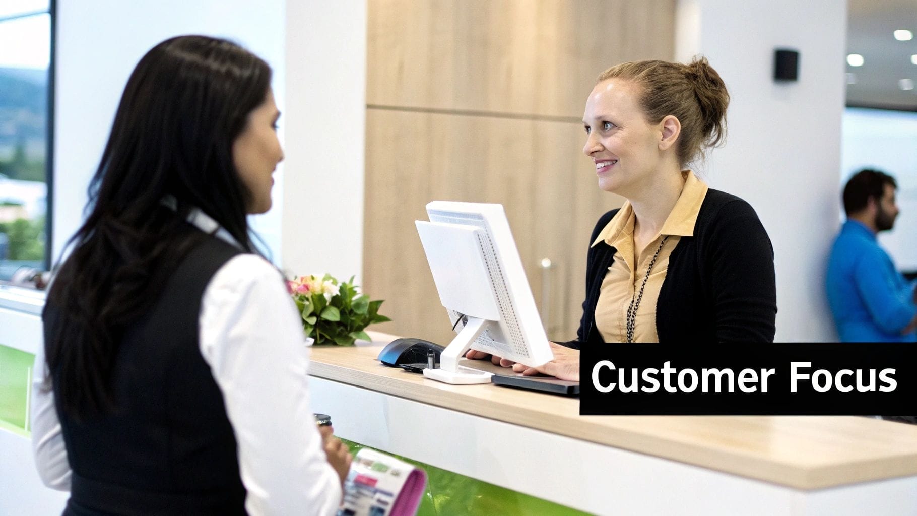 A woman stands at a reception desk talking to a receptionist, who is smiling at her—a perfect example of customer focus, which is essential for anyone looking to learn how to increase ecommerce sales.