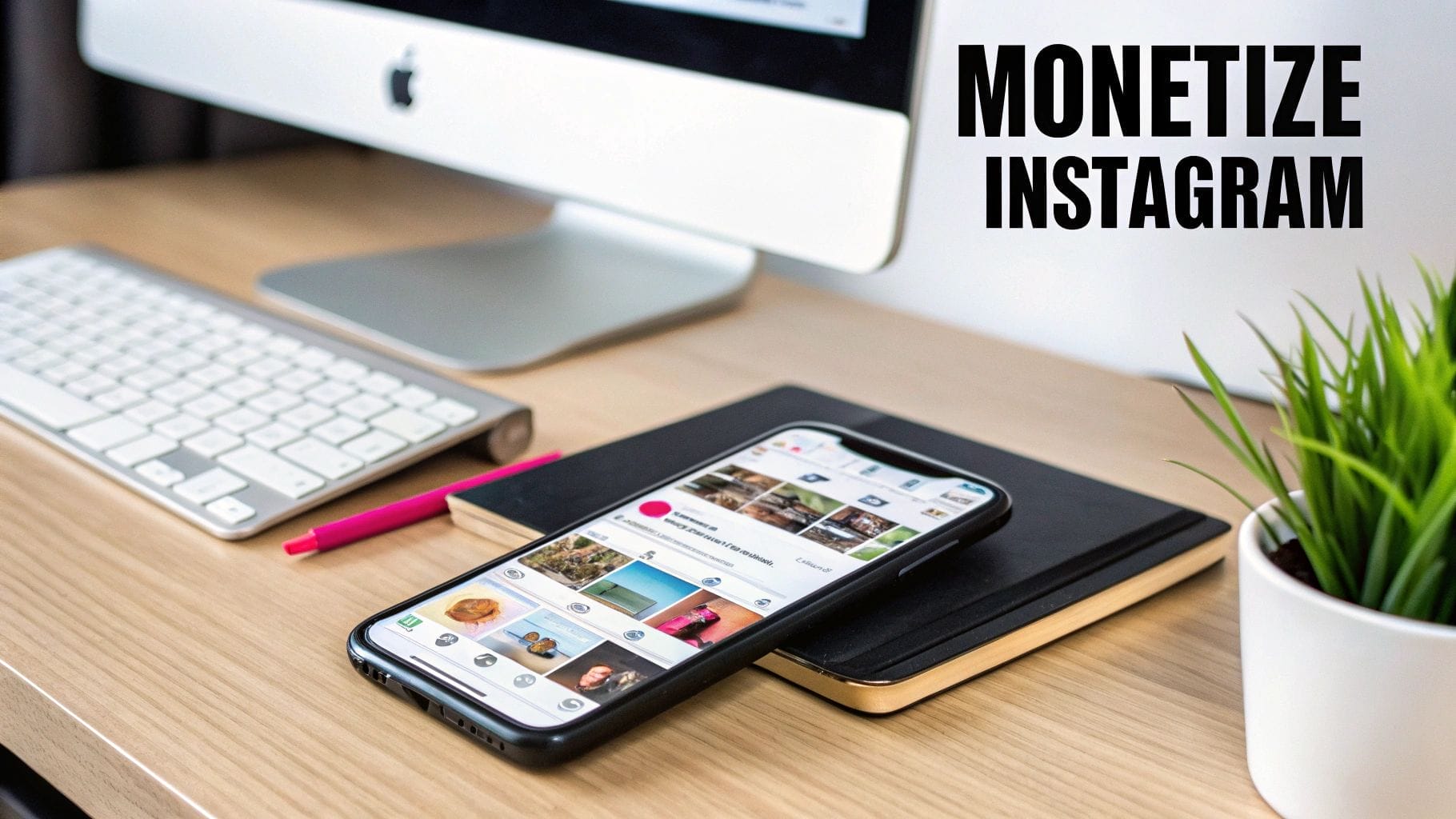 A smartphone displaying Instagram rests on a notebook beside a desktop computer, keyboard, pink pencil, and plant, with "MONETIZE INSTAGRAM" on the wall—perfect inspiration for learning how to monetize Instagram effectively.