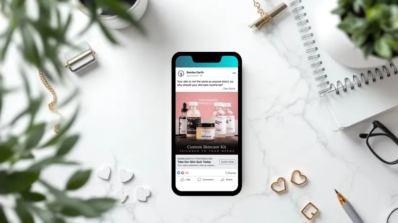 A smartphone on a marble desk displays a skincare ad, perfectly capturing effective small business marketing strategies. Surrounding items include a notepad, pen, potted plants, gold paperclip, and heart-shaped objects.